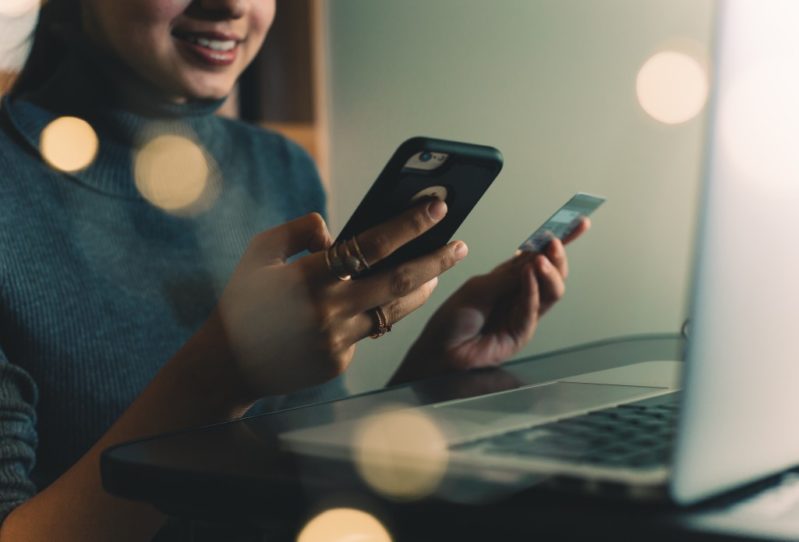 Woman looking at her phone and credit card using Earnin' 