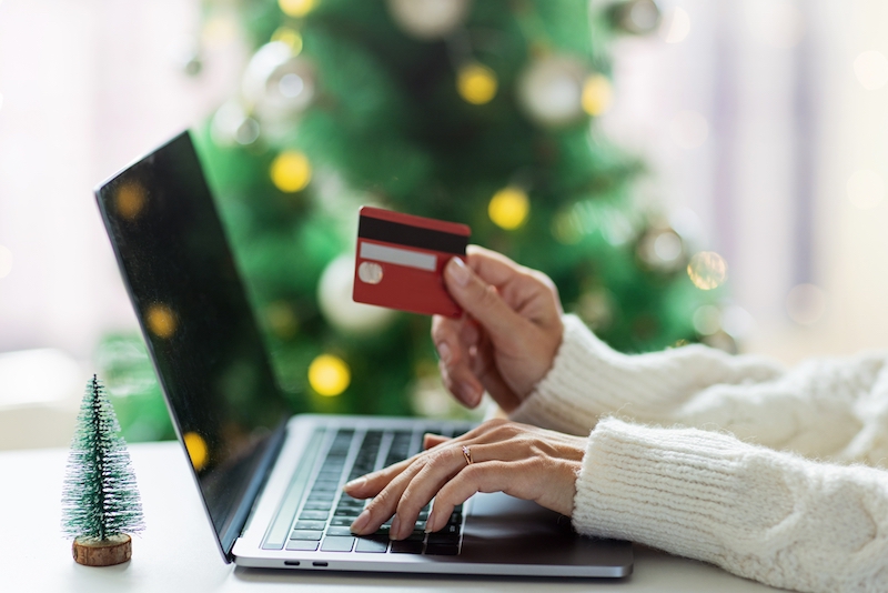 Young woman using holiday shopping tips to online shop for the holidays.