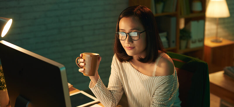 Young woman sitting at computer looking for data entry jobs from home.