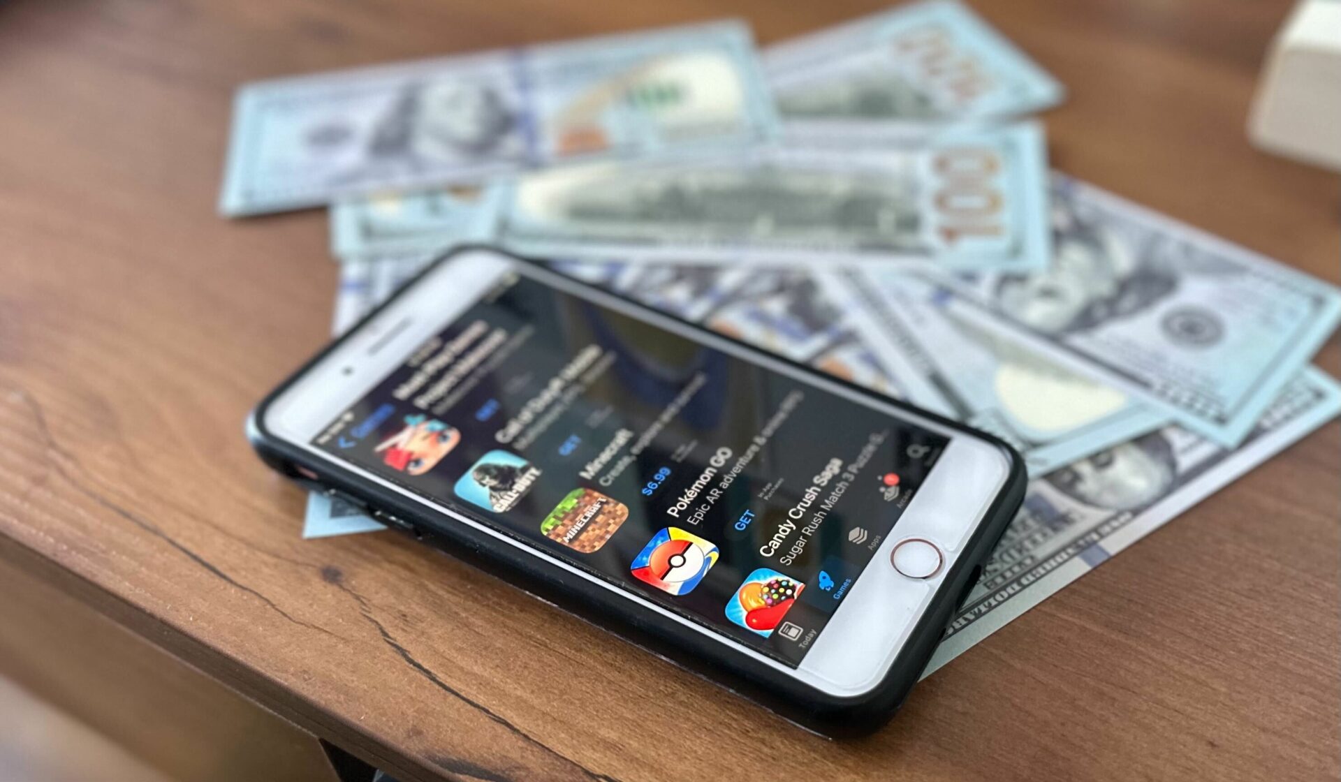 A phone with mobile gaming apps and cash on a table