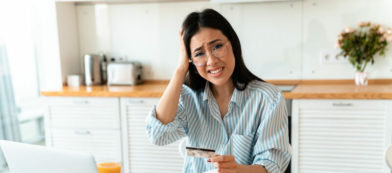 Woman sitting at computer wondering, "Are credit cards a trap?"