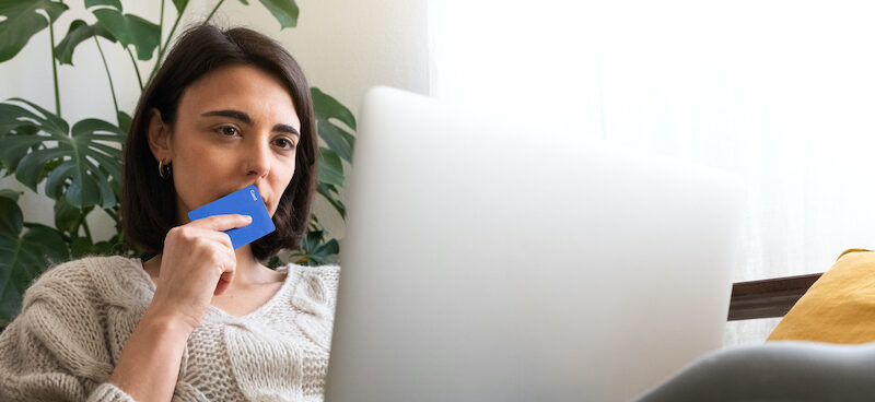 Young woman looking at laptop trying do answer, "Should I get a credit card?" for herself.