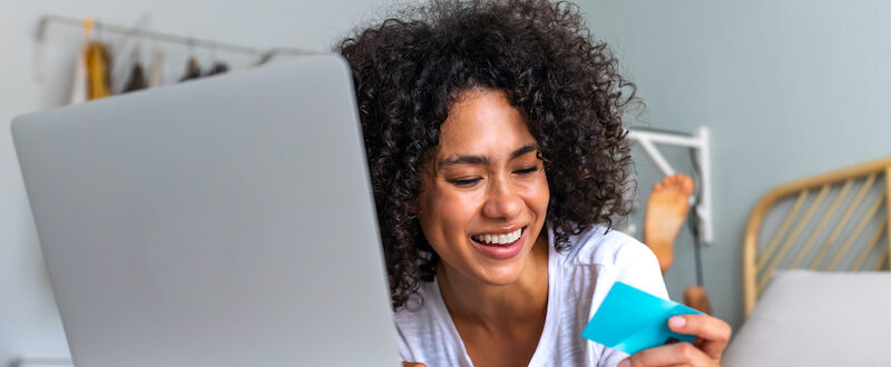 Young woman sitting at laptop looking up "how do credit cards work?"