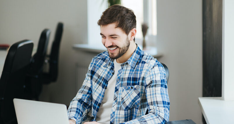 Young man excited to start earning extra cash online after reading an iPoll review.
