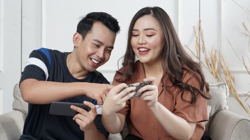 Two young people looking up how to earn gift cards by playing games on their mobile devices. 