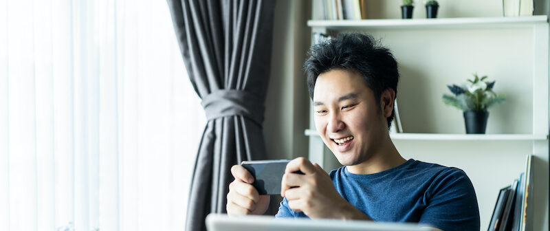 Young man trying to earn gift cards by playing games on his mobile device.
