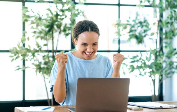 Young woman smiling at computer while earning extra money online after reading a Surveytime review.