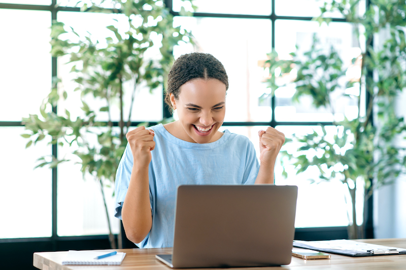 Young woman smiling at computer while earning extra money online after reading a Surveytime review.