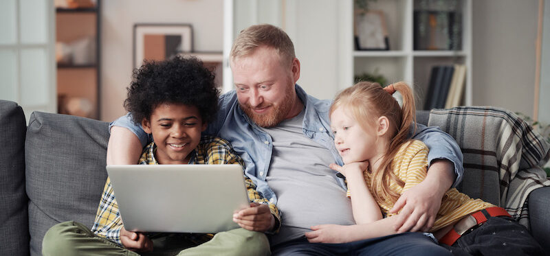 Parent with two children completing online surveys for kids together.
