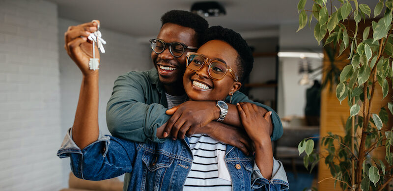 Happy couple holding keys to their new home they were able to fund after reading this Warp Speed Mortgage review.