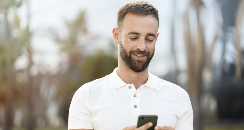 A man looking happy after successfully sending money from his phone after reading a Pangea Money Transfer review.