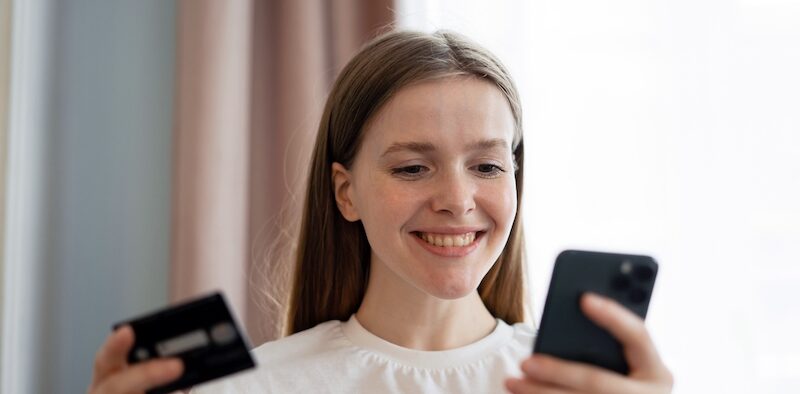 Young woman reading a Current Bank review on her mobile phone.