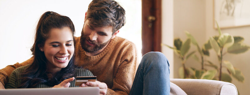 A young couple reading a PenFed credit card review online.