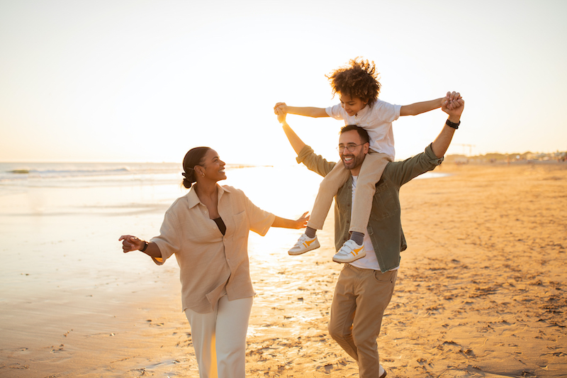 Young family strolling on the beach after reading a Fabric life insurance review together.