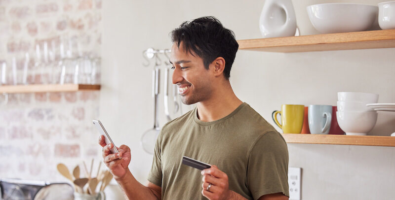 Man is smiling at his phone while he earns free Visa gift cards online.