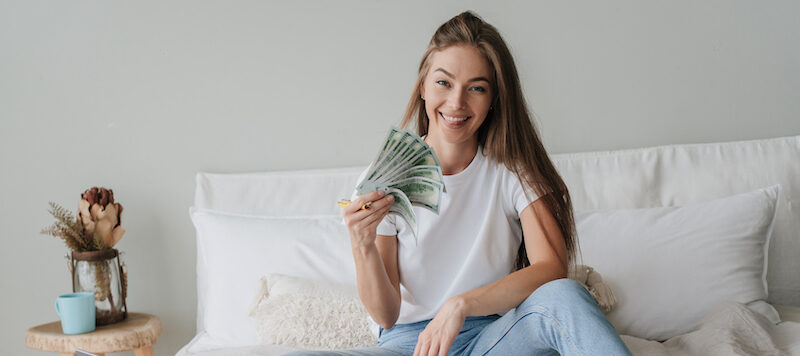 Young woman holding the cash she got from early direct deposit.