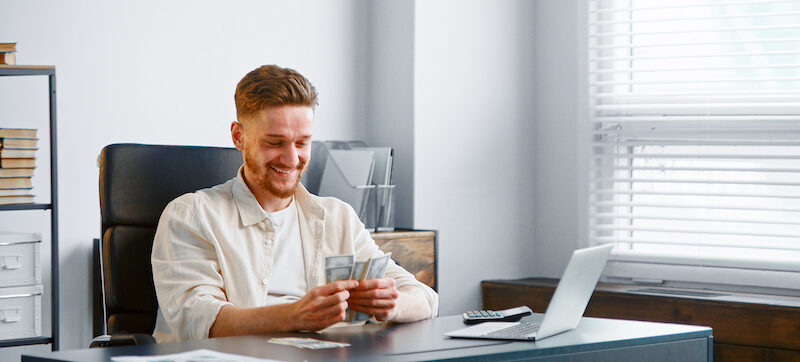 Young man counting his savings after completing the Biweekly Money Saving Challenge.