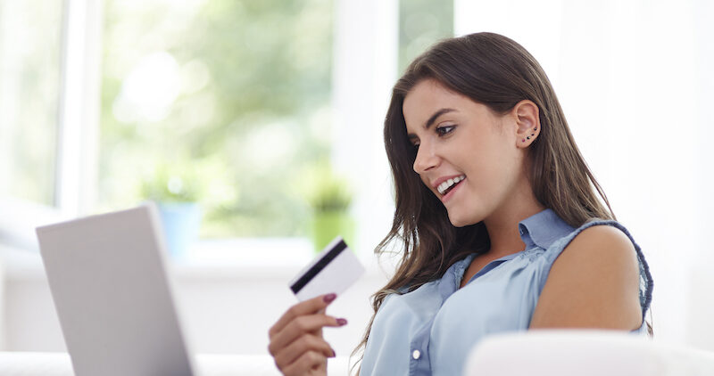 A young woman reading a Credit Strong review on her laptop.