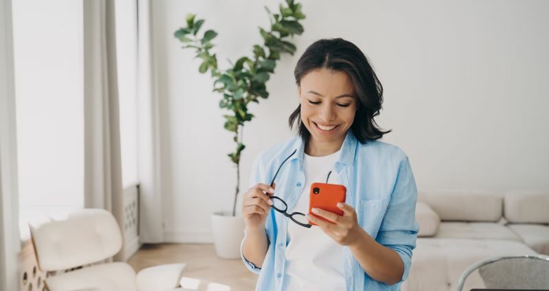 Woman smiling at phone in living room