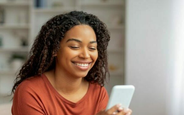 Woman smiling at cell phone in living room