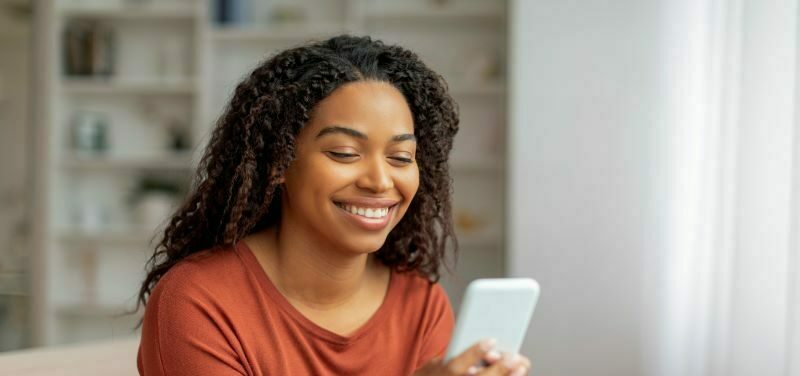 Woman smiling at cell phone in living room