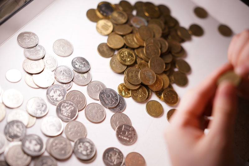 A person counting coins from Goldco vs Augusta Precious Metals.