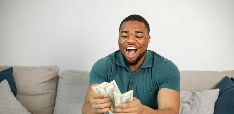 Happy man on sofa counting cash