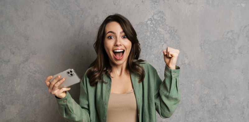 Excited woman holding her phone after winning game