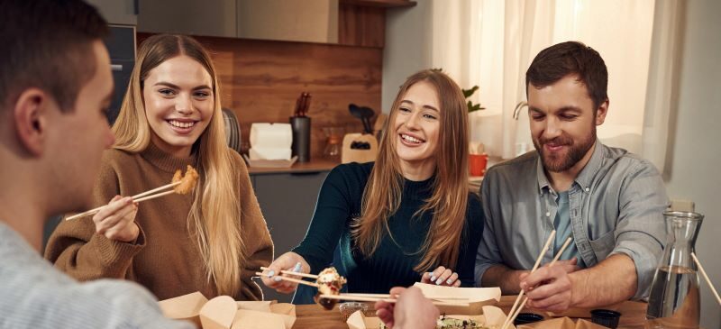 Friends eating takeout at the kitchen table