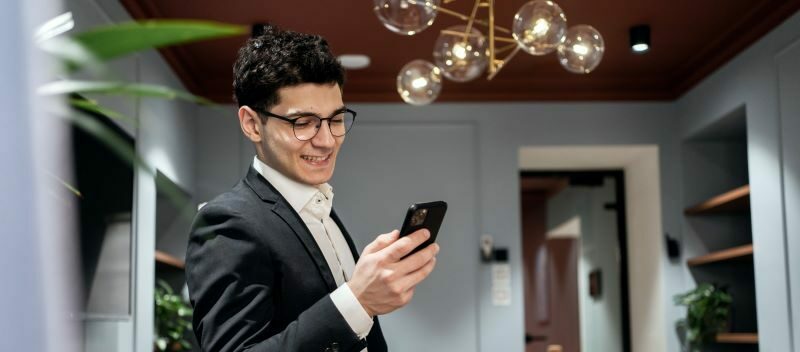 Man in suit smiling down at his cell phone