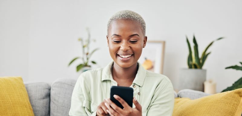 Woman on sofa smiling at cell phone