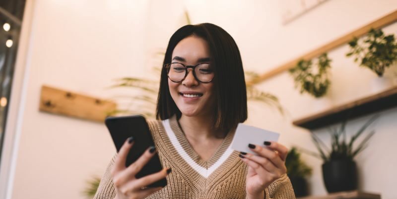 Woman holding card and smiling at phone