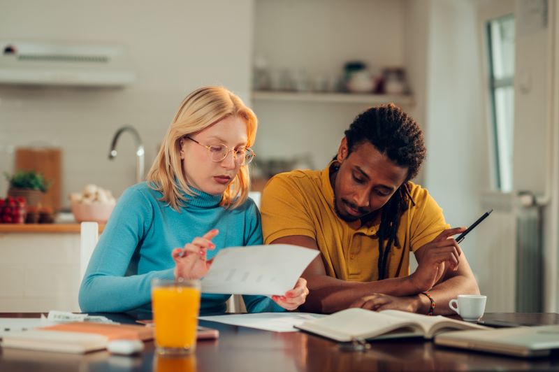 Couple going over bills at kitchen table.