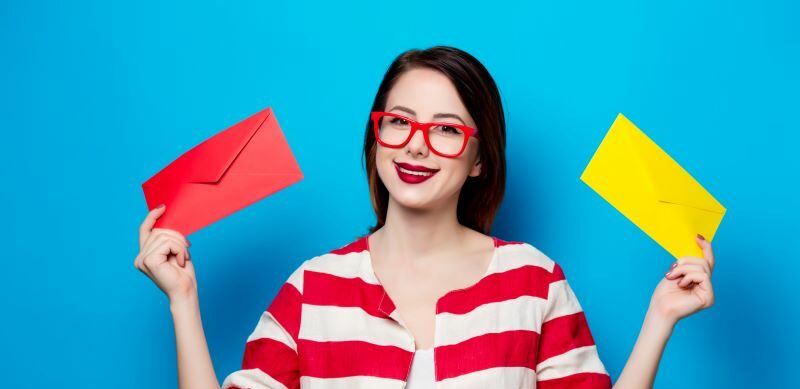 Woman smiling holding two brigthly colored envelopes