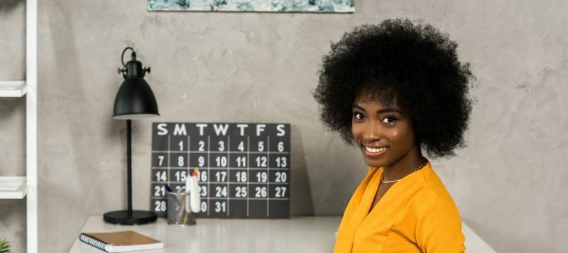 Woman smiling at desk with calendar.