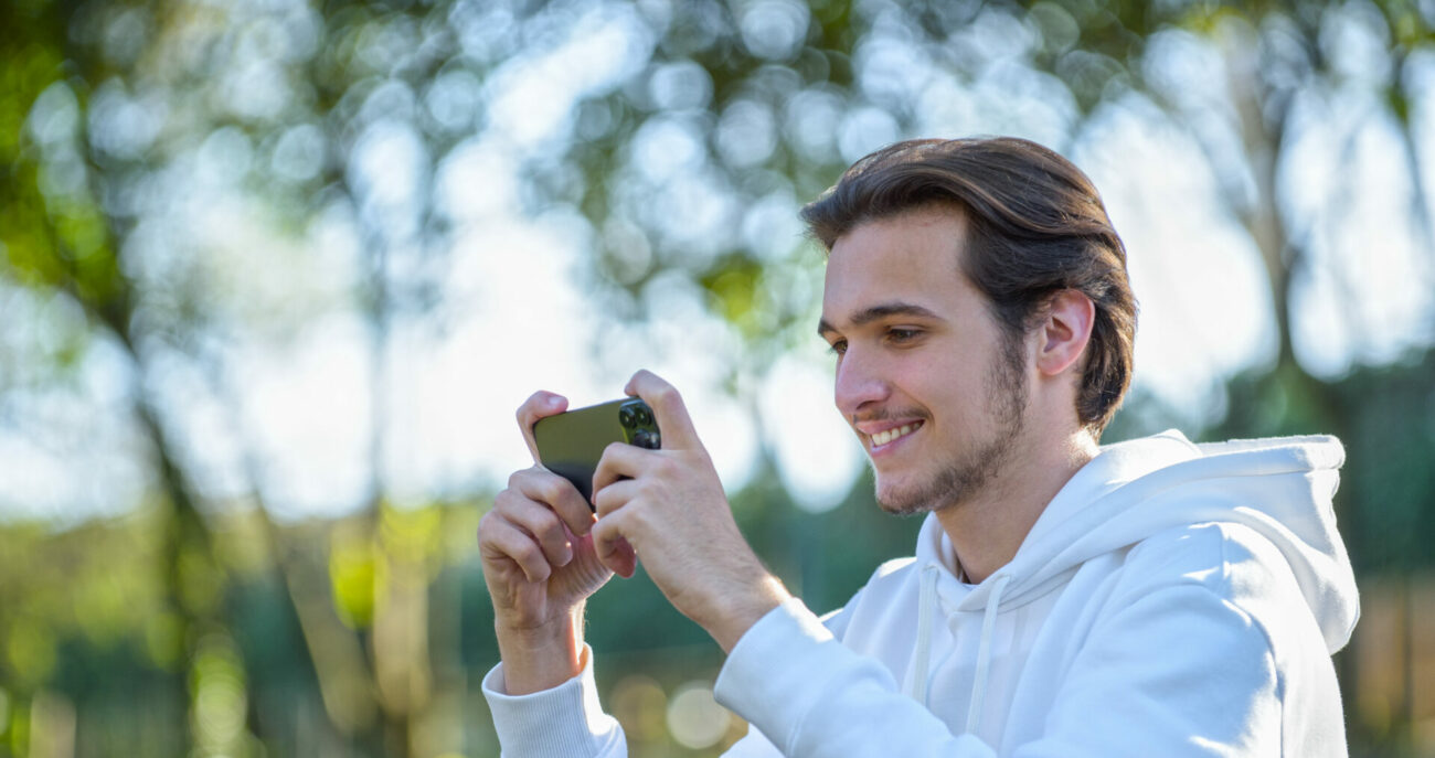 Smiling man looking at cell phone outside