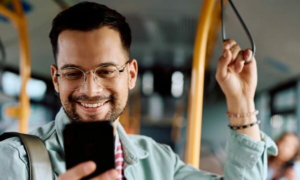 Man on bus smiling at cell phone