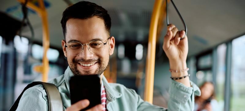Man on bus smiling at cell phone