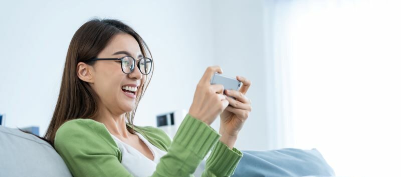Woman smiling playing phone game on sofa