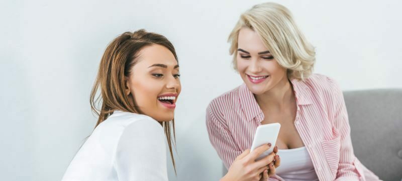 Two women smiling looking at cell phone