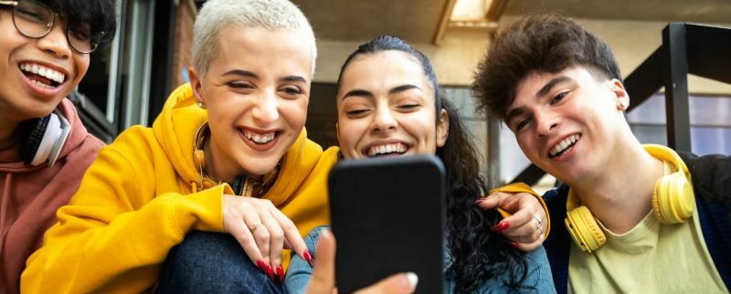 Teens smiling looking at cell phone