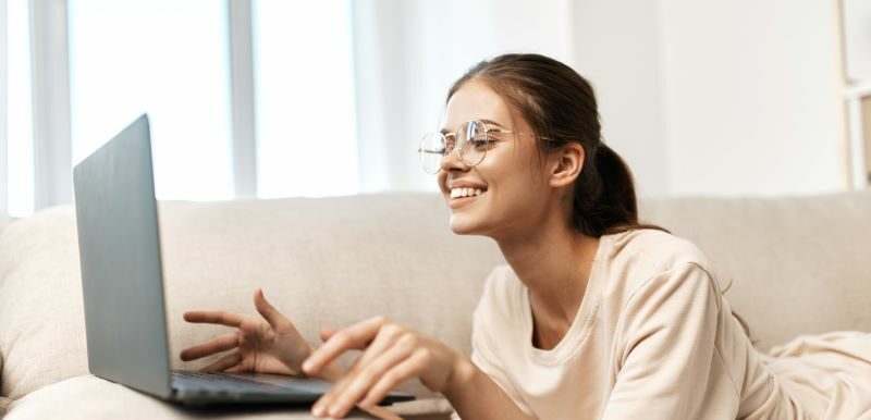 Woman on sofa smiling at laptop