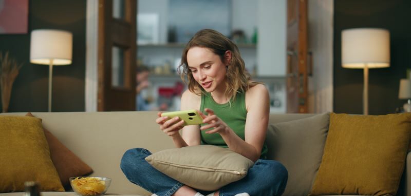woman on sofa smiling at phone