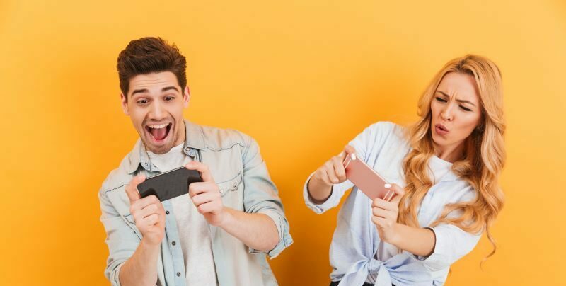 Two people playing competing phone games