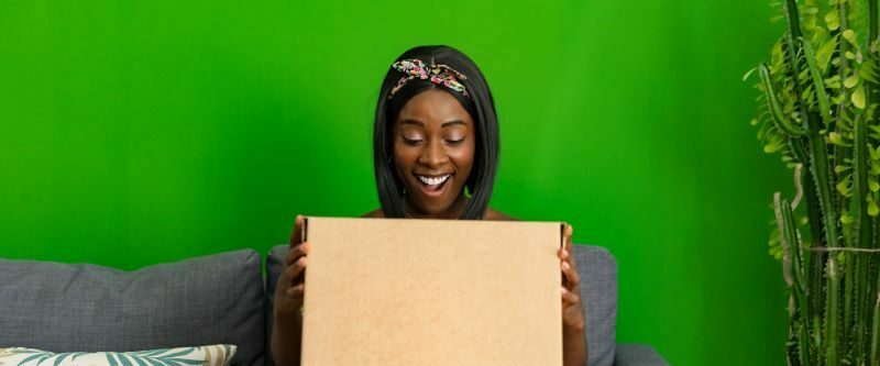 Woman on sofa with package smiling