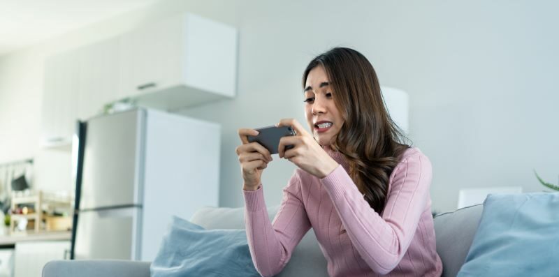 Woman playing cell phone game on sofa