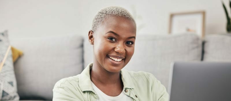 woman smiling at camera while working at laptop at home