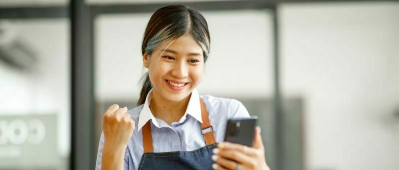 Worker pumping fist and smiling looking at cell phone