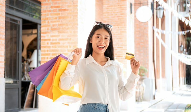 Woman smiling holding shopping bags and credit card