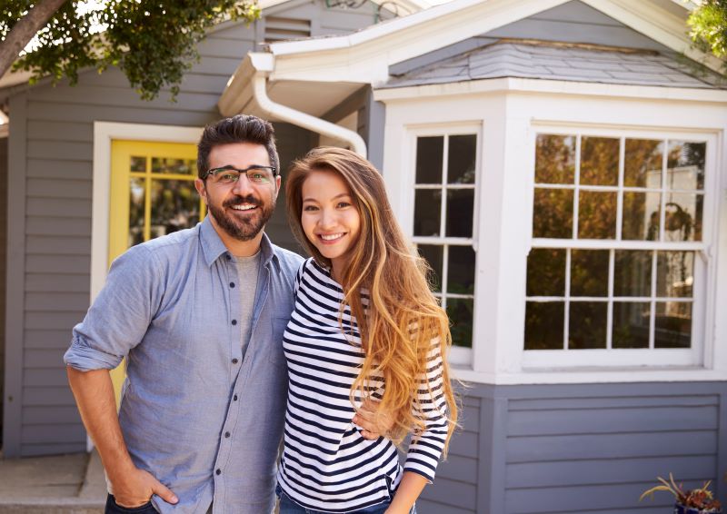 Couple standing in front of home smiling at camera